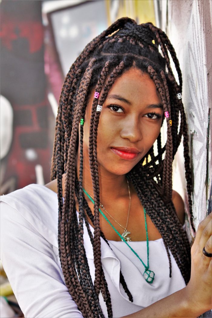 Close-up portrait of a woman with braided hair against a colorful urban backdrop.