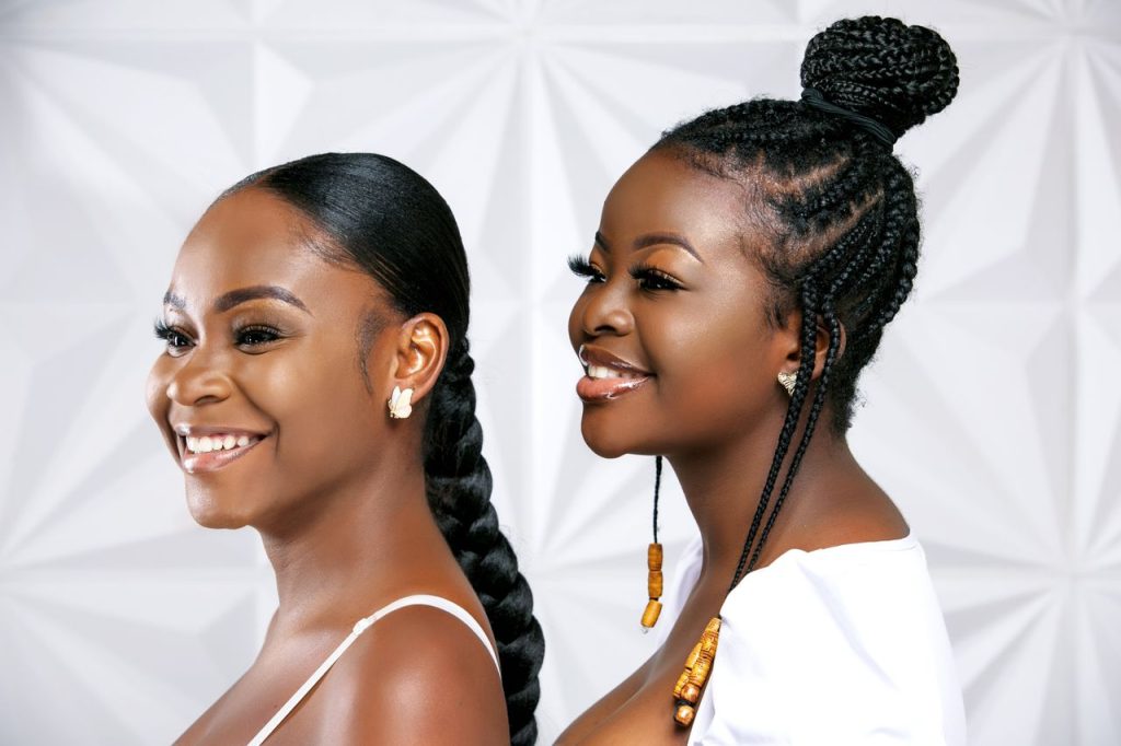 Smiling portrait of two black women with stylish braids, showcasing beauty and elegance.