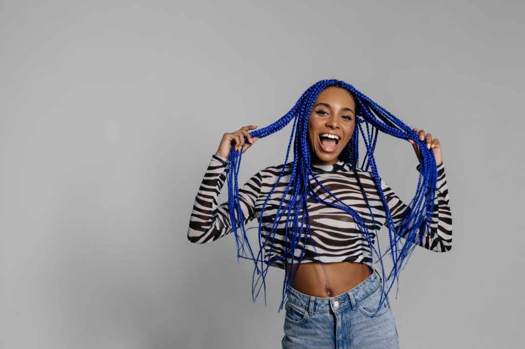 Stylish woman with blue braided hair in animal print crop top posing in studio.